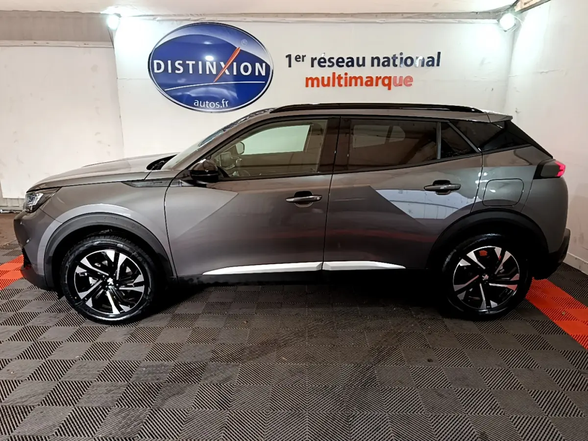 Profil côté gauche du Peugeot 2008 gris foncé 2022 dans un showroom avec jantes noires et détails chromés.