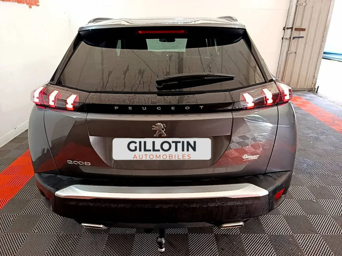Vue arrière d'un Peugeot 2008 gris foncé avec feux LED caractéristiques et attelage visible.