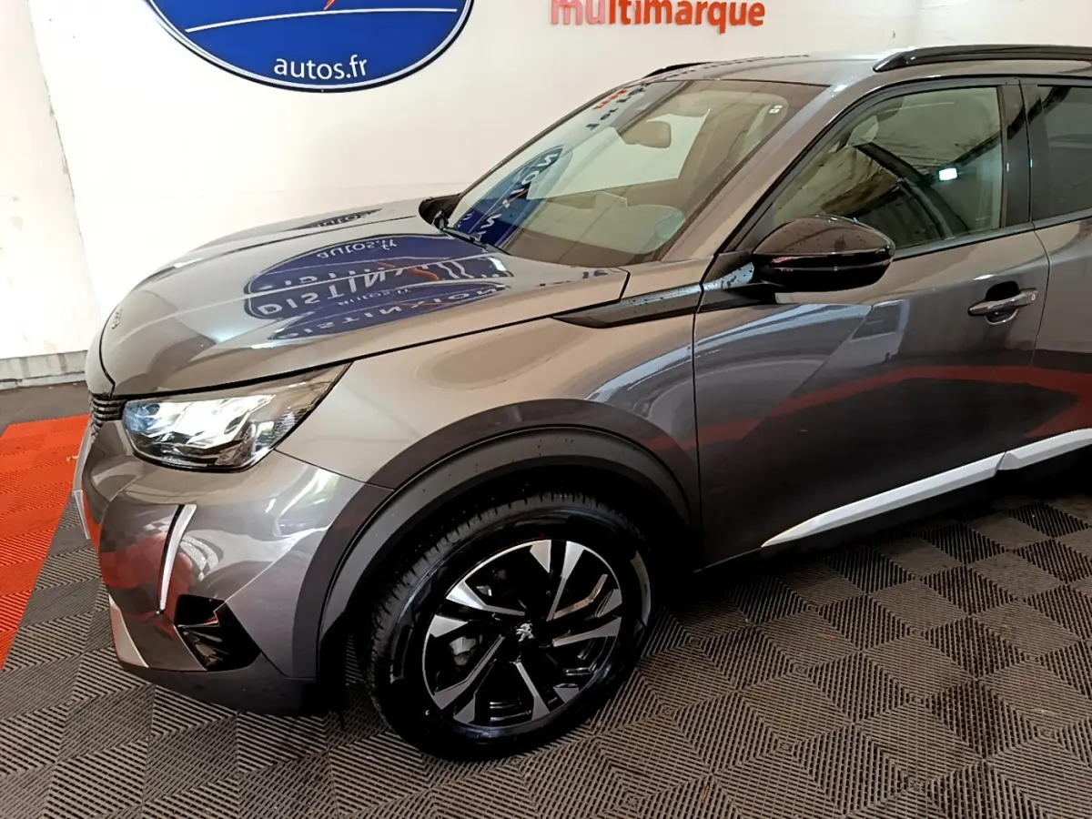 Vue 3/4 avant droit d'un Peugeot 2008 gris foncé avec jantes noires et détails chromés sur les ailes.