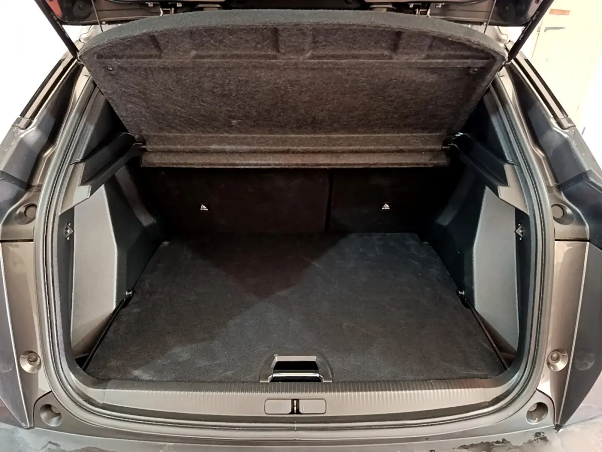 Coffre ouvert vu de l'arrière d'un Peugeot 2008 gris foncé avec plancher plat et tablette de séparation relevée.