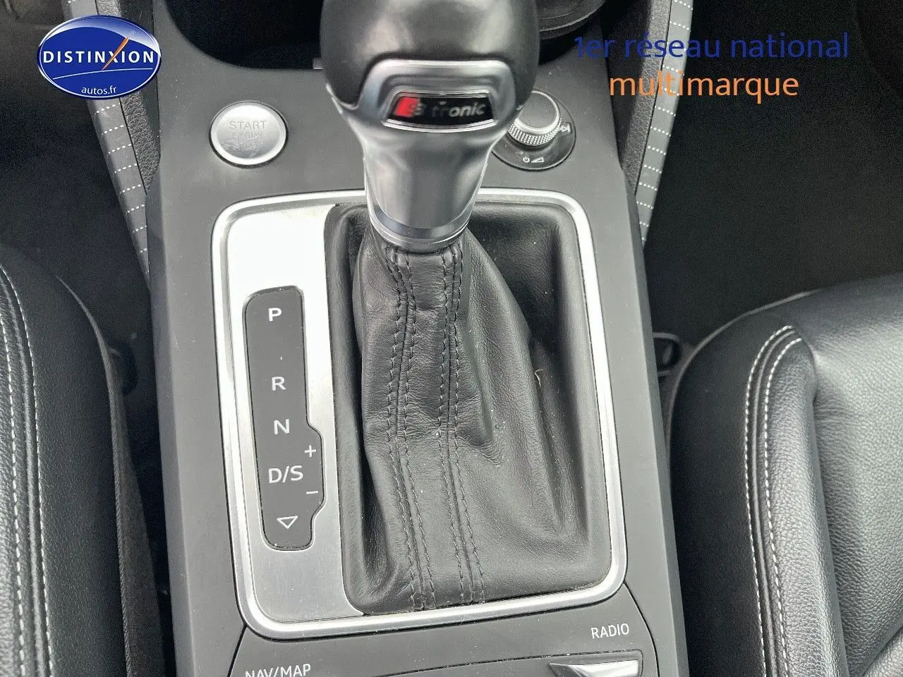Gros plan sur la console centrale d'Audi Q2 avec levier de vitesses S tronic en cuir noir et accoudoir latéral.