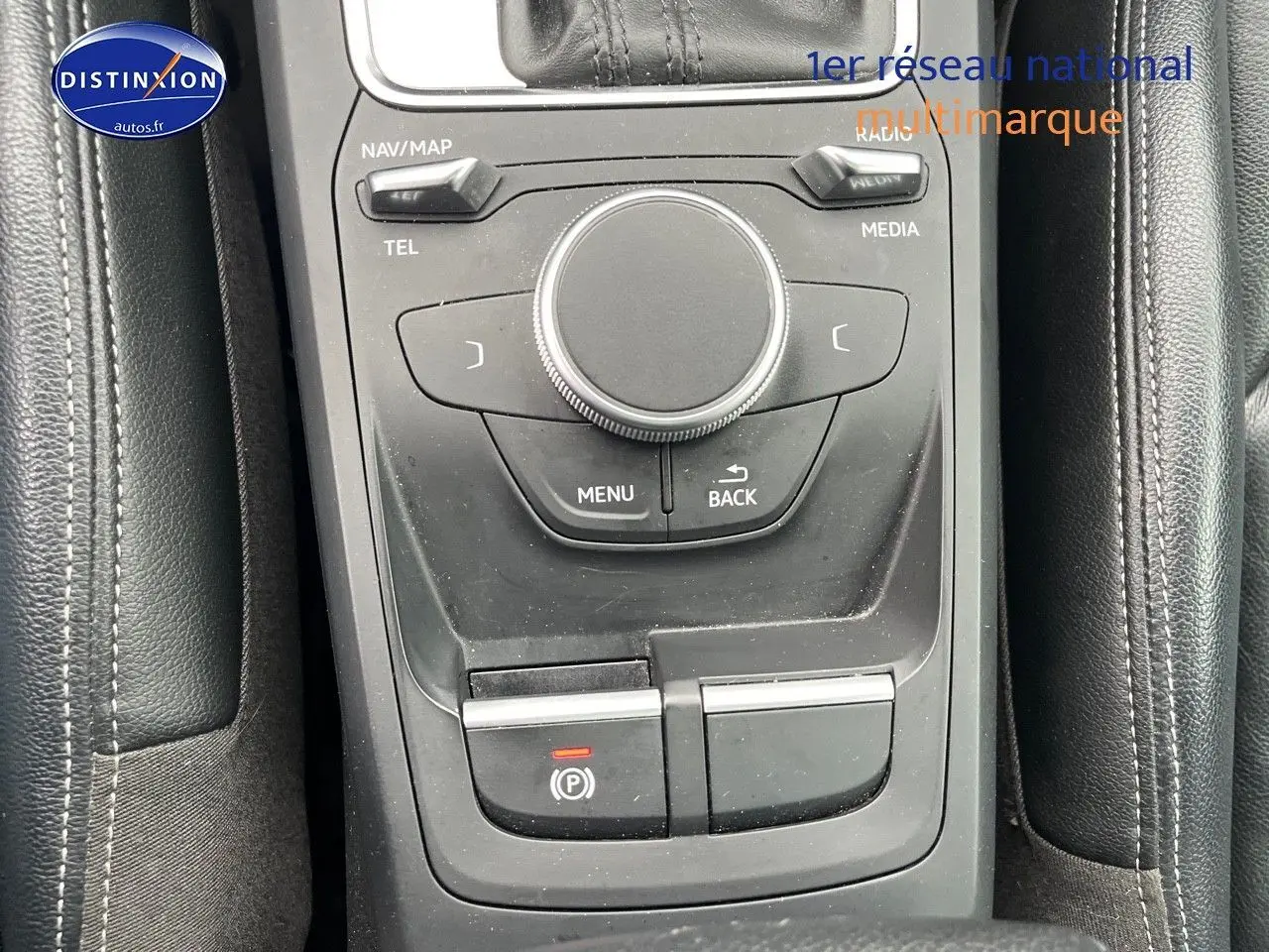 Vue rapprochée de la console centrale noire avec commandes multimédia et frein à main électrique d'Audi Q2.
