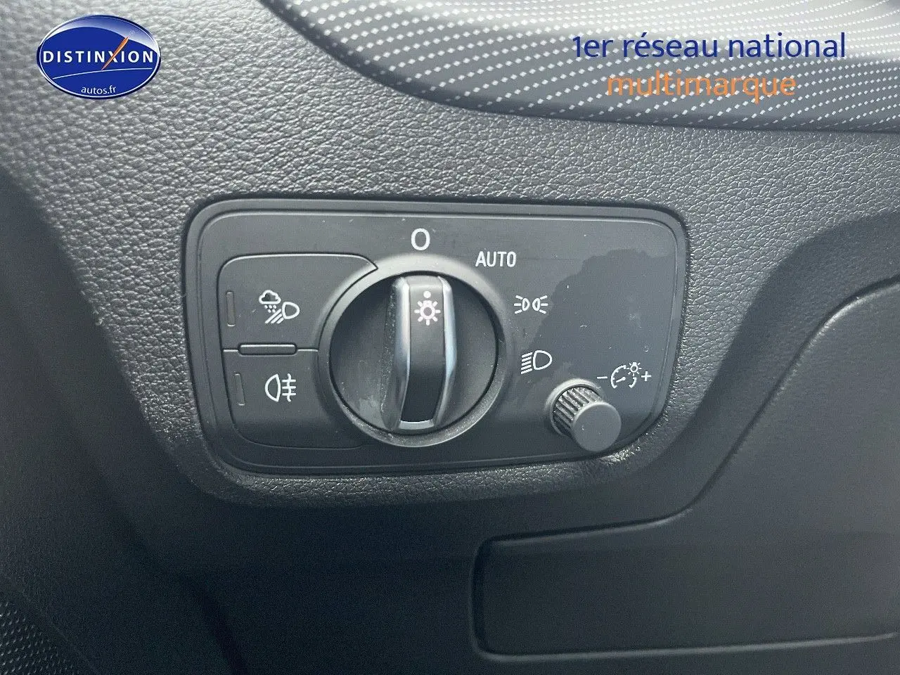 Gros plan sur le bouton de commande des phares dans l’habitacle de l’Audi Q2 blanc Ibis, côté gauche.