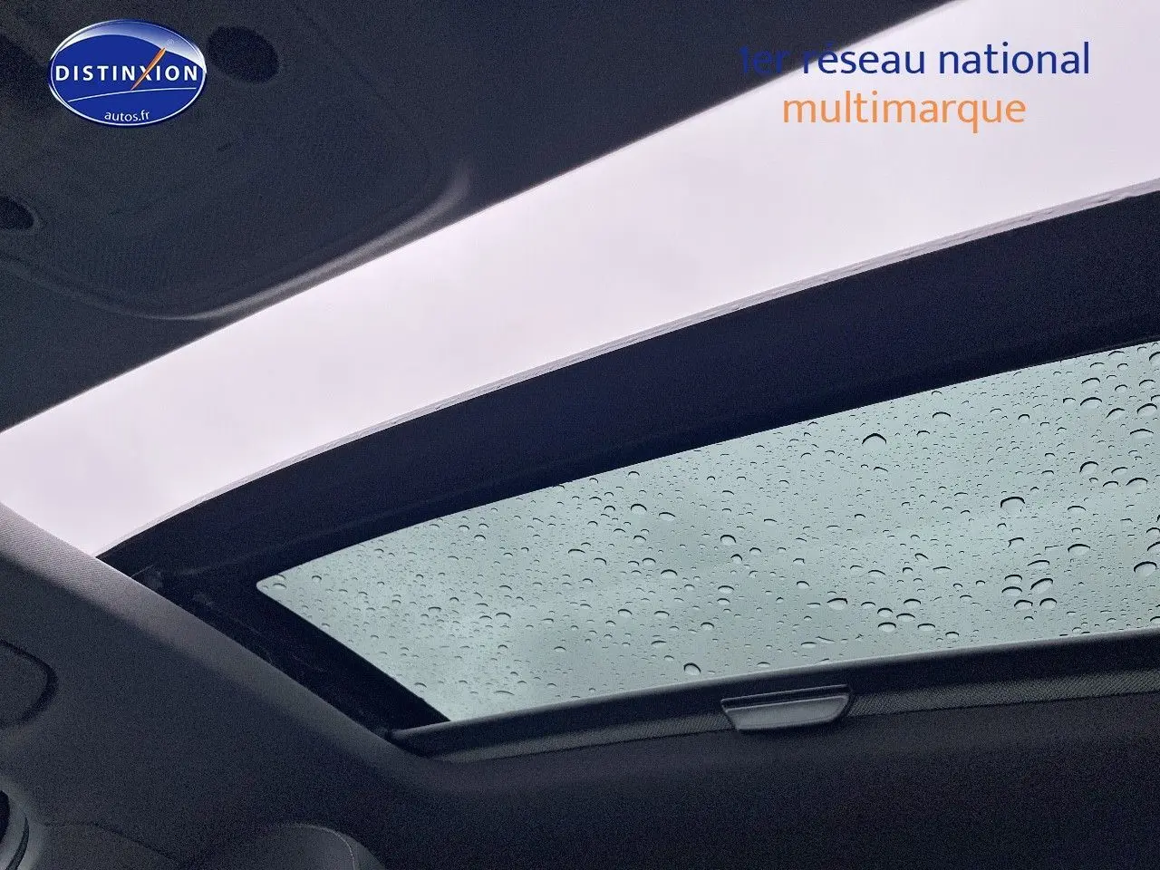 Toit ouvrant électrique coulissant d'un Audi Q2 blanc Ibis vu de l'intérieur avec gouttes de pluie visibles sur la vitre.