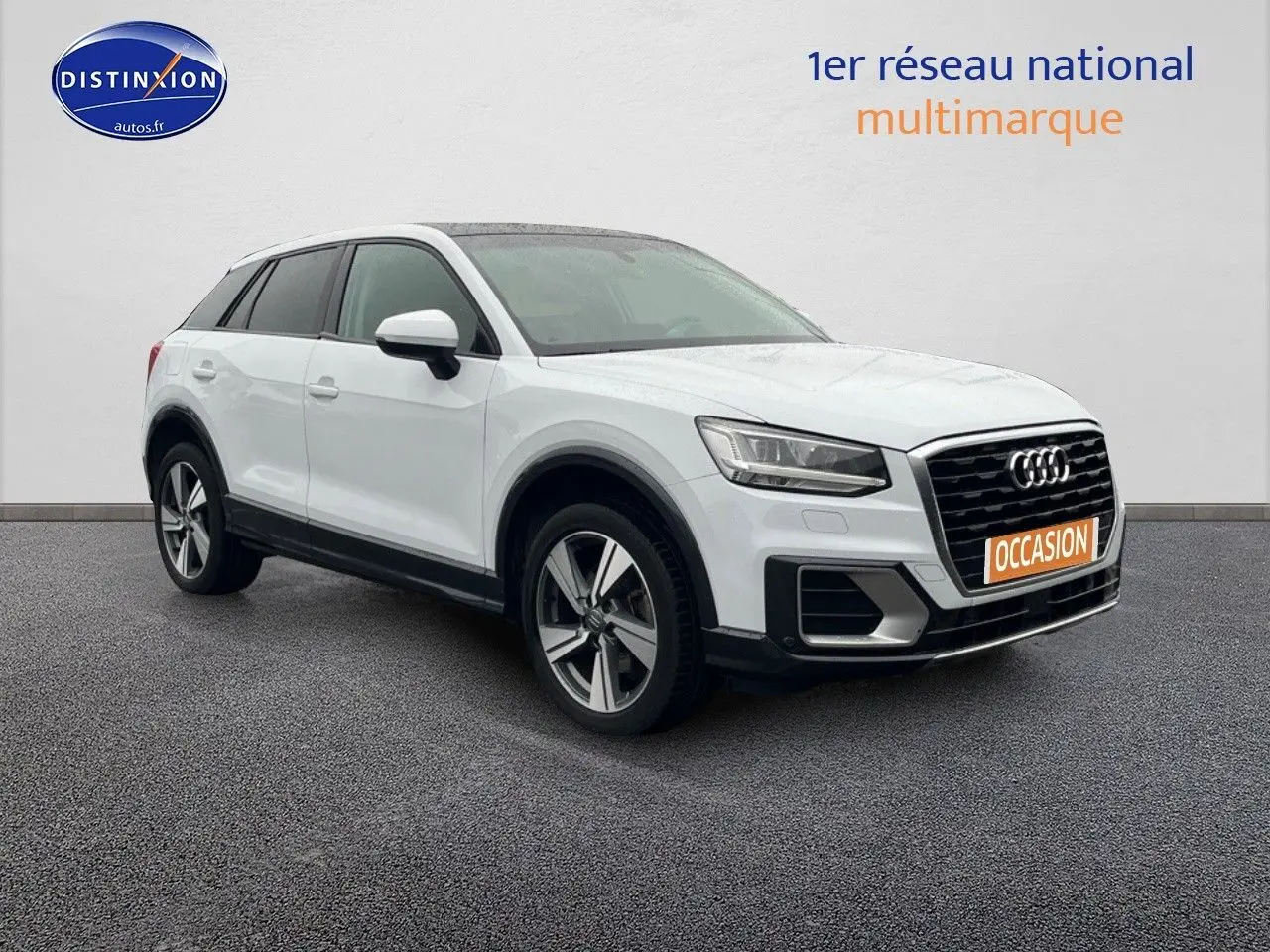 Audi Q2 blanc Ibis en vue 3/4 avant droit, avec jantes alliage 18 pouces et toit ouvrant électrique visible.