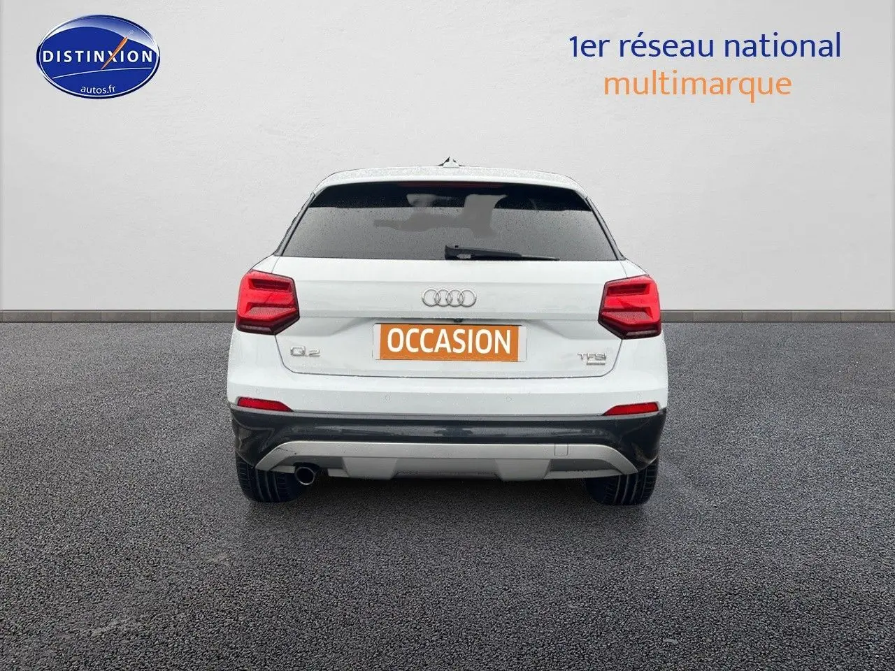 Vue arrière d'un Audi Q2 blanc Ibis de 2018 avec feux rouges et plaque "OCCASION" visible sur fond neutre.