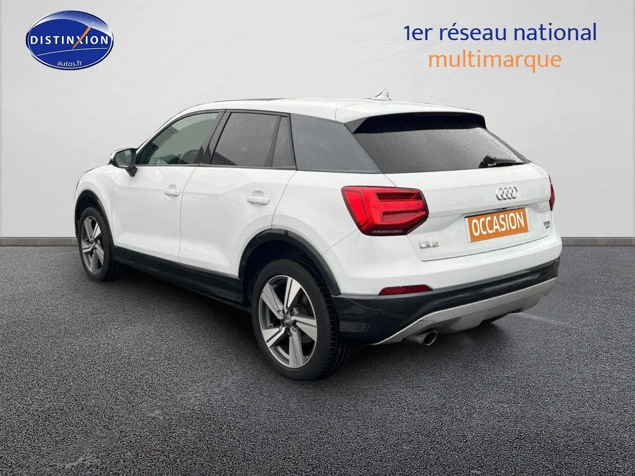 Audi Q2 blanc Ibis en 3/4 arrière droit avec jantes alu 18 pouces et vitres surteintées.