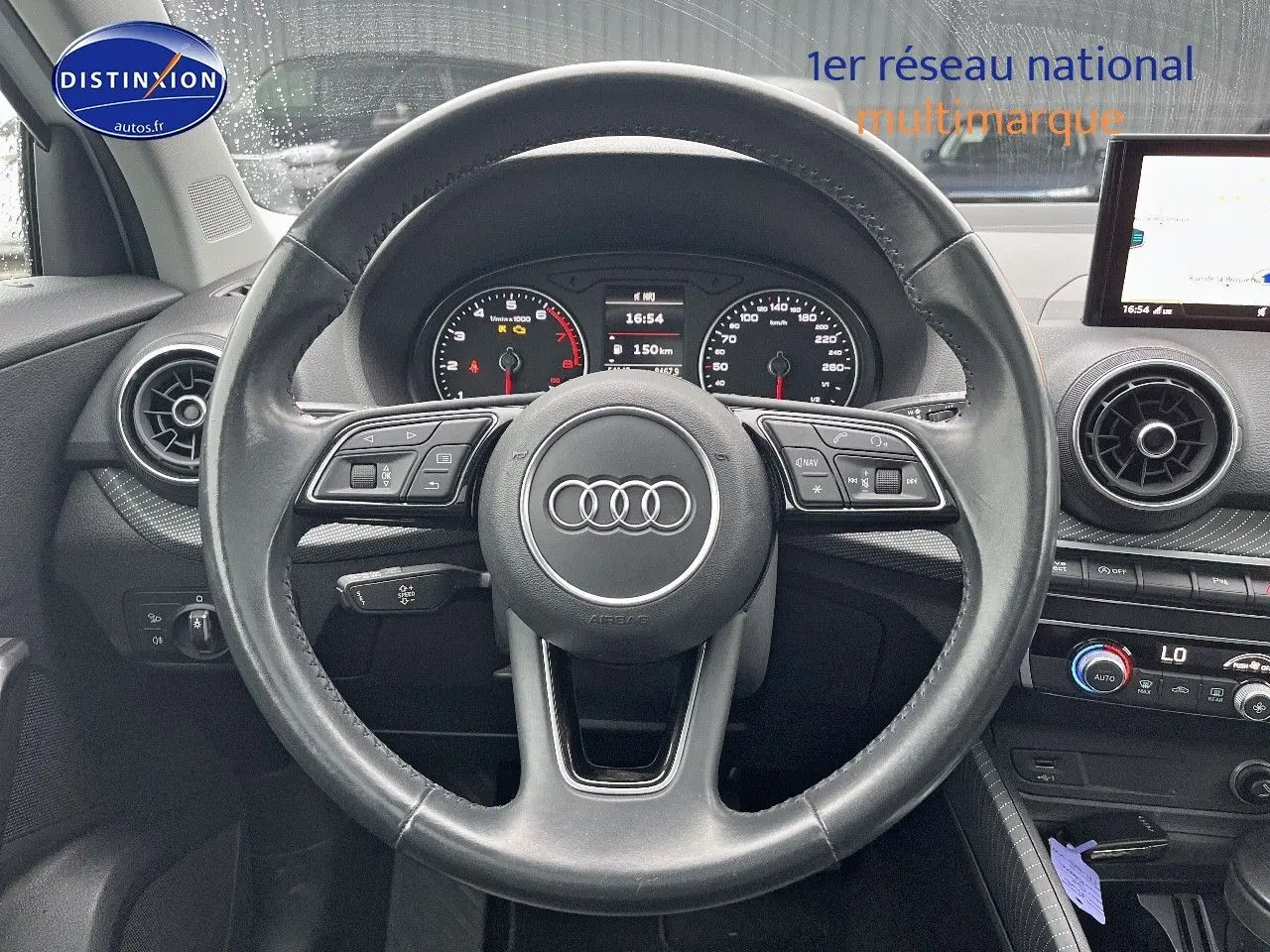 Vue frontale du volant cuir noir multifonction de l'Audi Q2 2018 avec tableau de bord et écran central visibles.