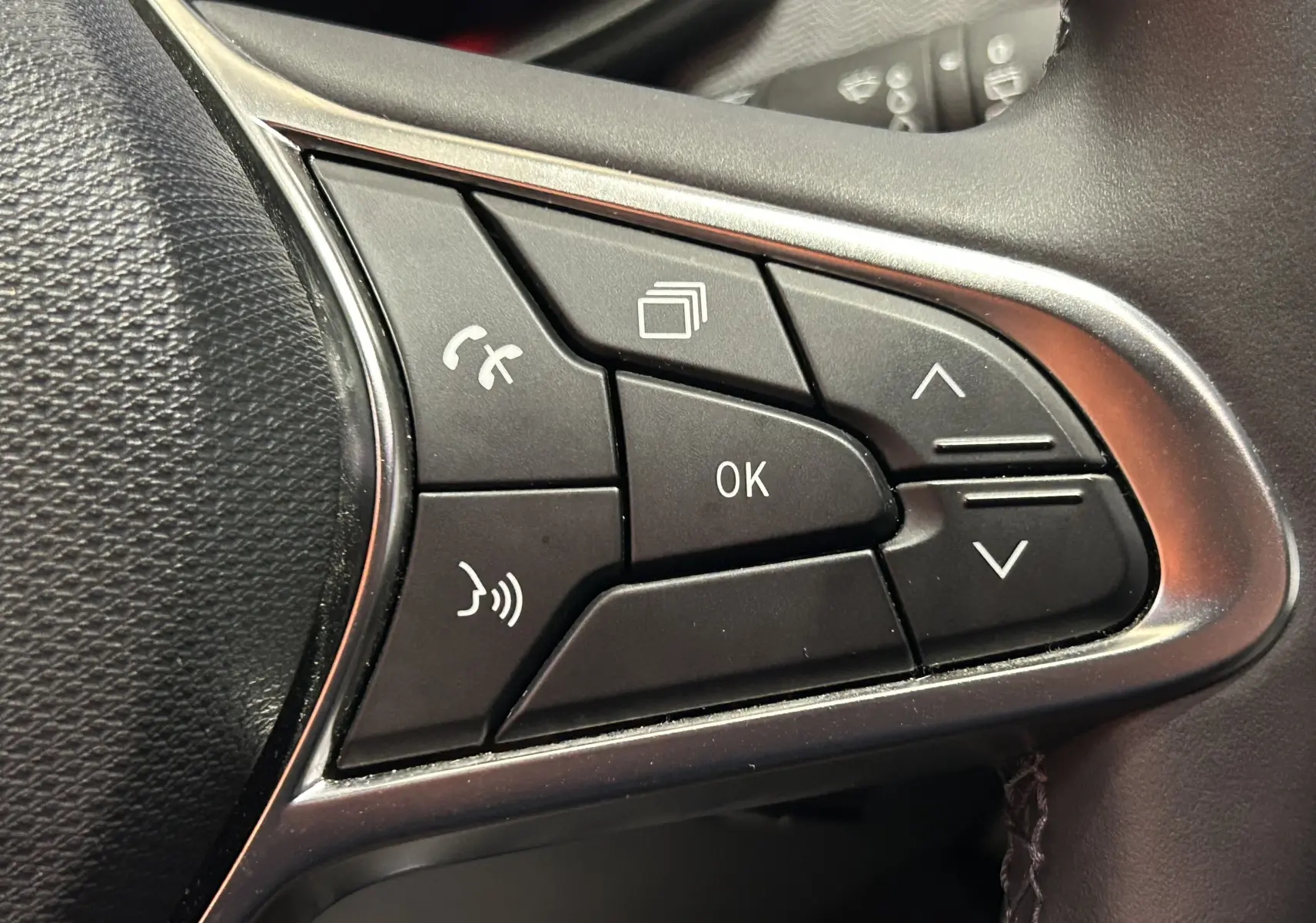 Gros plan sur les commandes multifonctions noires du volant côté droit de la Renault Clio V hybride 2025.