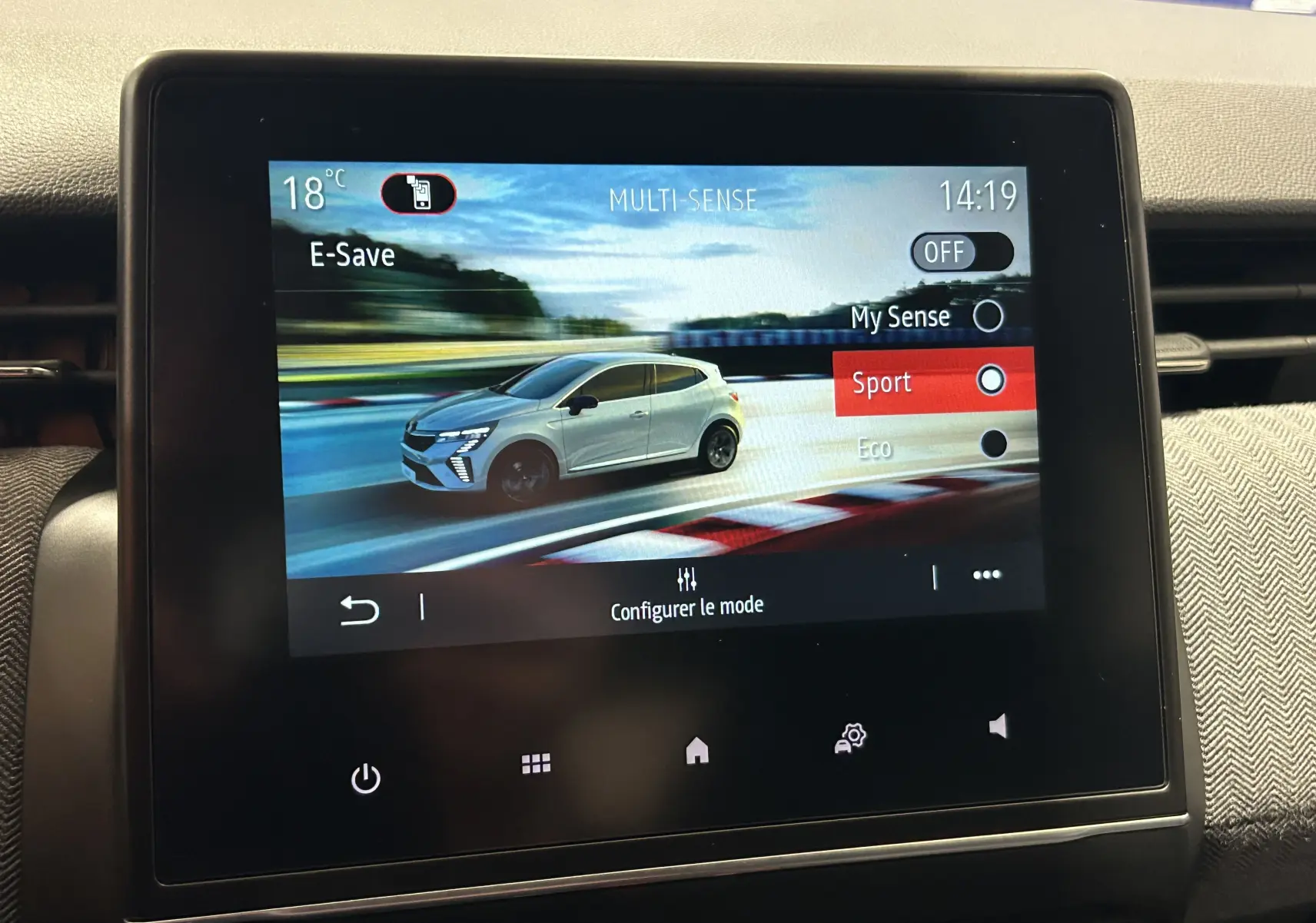 Écran tactile intérieur montrant une Renault Clio V gris rafale en mode Sport, vue 3/4 avant droite.