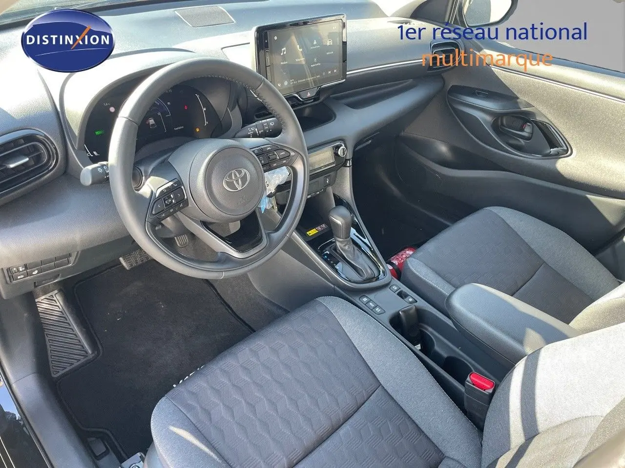 Vue intérieure côté conducteur de la Toyota Yaris Hybrid 116ch 2025 avec sièges tissu noir et tableau de bord moderne.