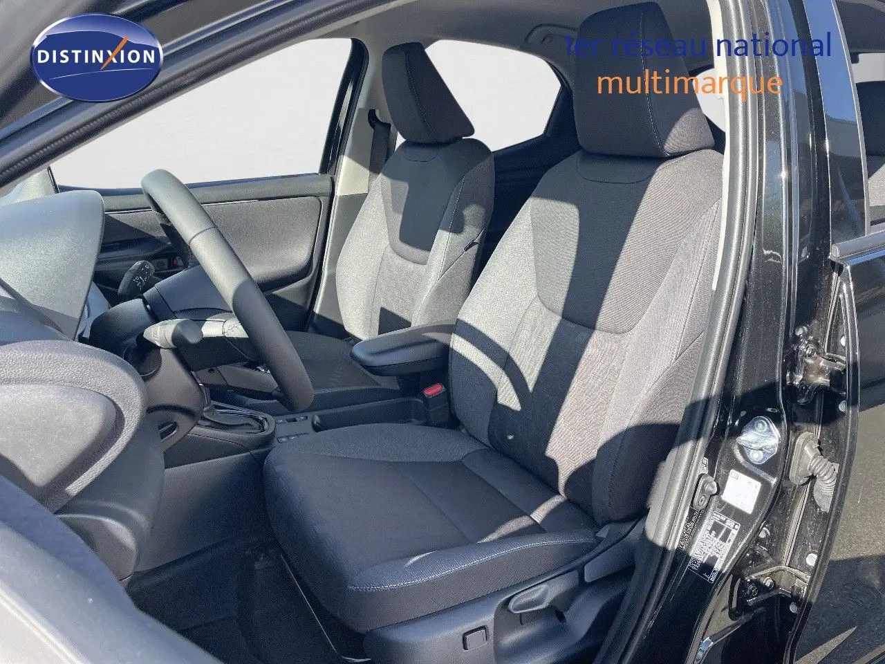 Vue intérieure côté conducteur de la Toyota Yaris Hybrid 116ch Design 2025 en noir métal, sièges tissu gris.