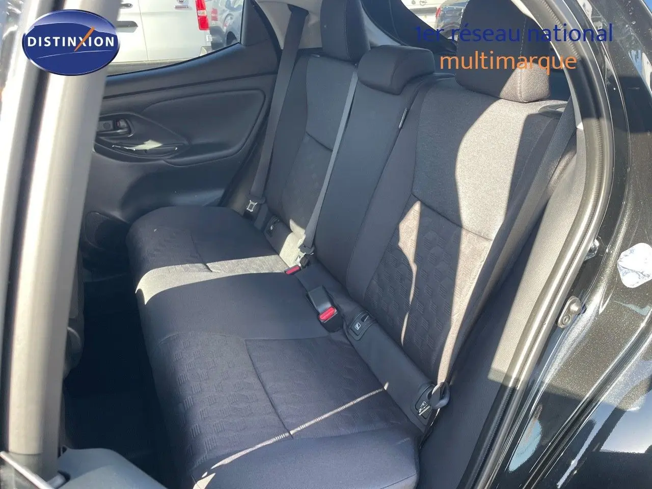 Vue intérieure arrière côté droit de la Toyota Yaris Hybrid 116ch 2025 avec sièges tissu noir et porte ouverte noir métal.