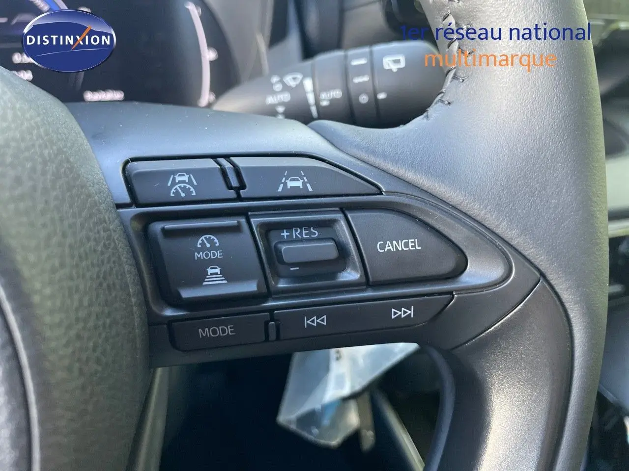 Gros plan sur les commandes au volant d'une Toyota Yaris Hybrid 2025, boutons de régulateur et aides à la conduite visibles.