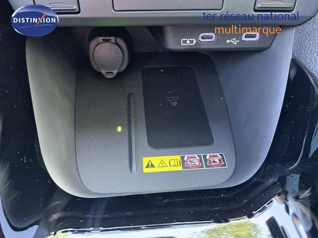 Vue rapprochée du chargeur sans fil et des ports USB dans l'habitacle noir métal de la Toyota Yaris Hybrid 2025.