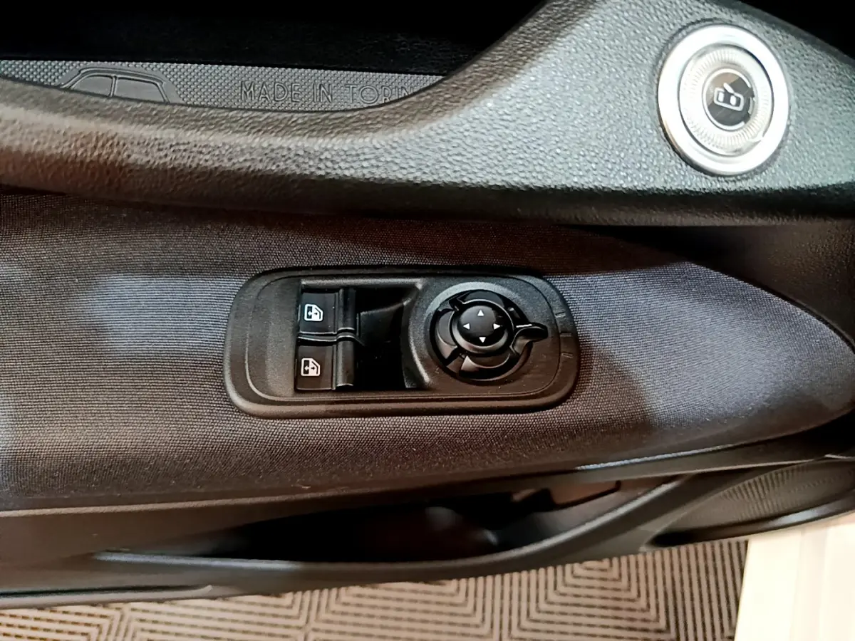 Détail des commandes de lève-vitres et réglage des rétroviseurs sur la porte côté conducteur d'une Fiat 500 blanche 2022.