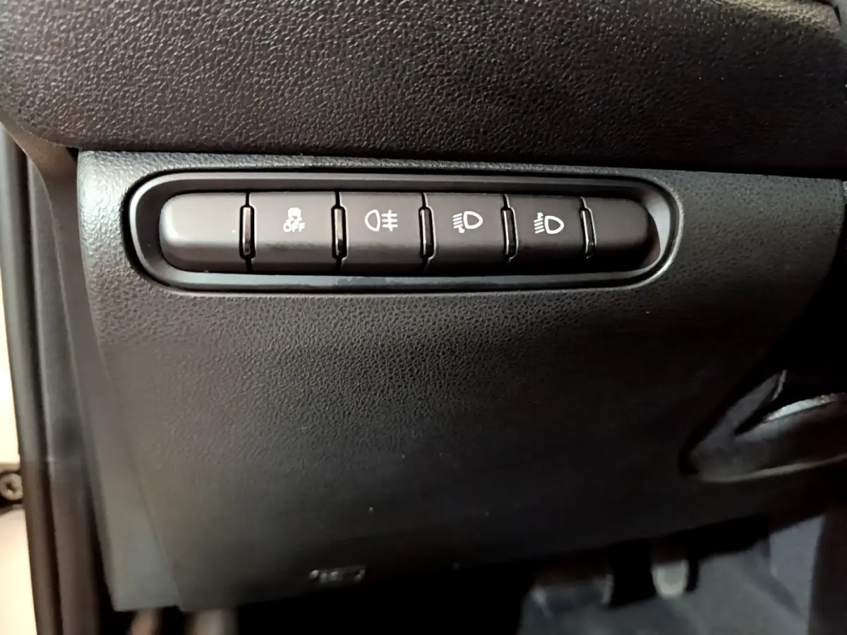 Boutons de commande des feux et de l'antipatinage sur la planche de bord noire d'une Fiat 500 blanche électrique 2022.