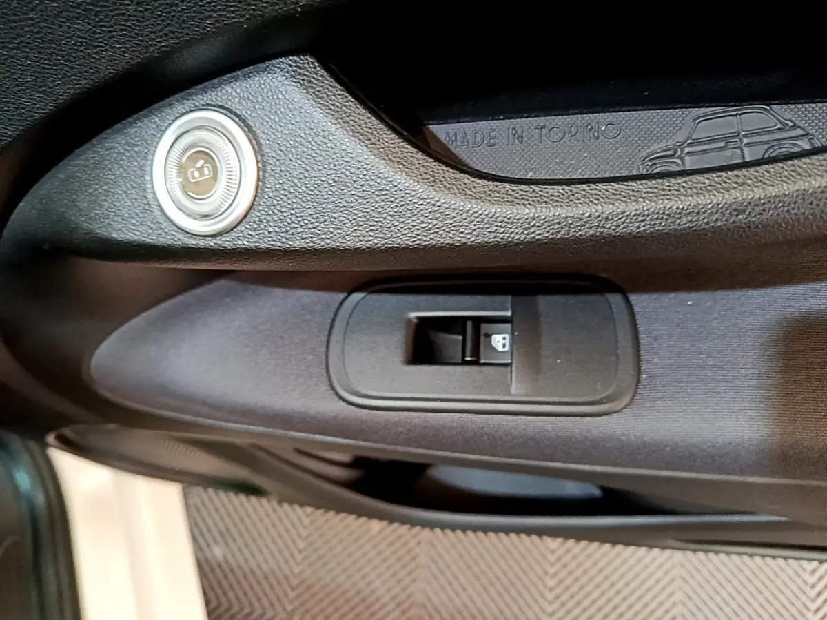 Gros plan sur la commande de verrouillage de porte côté gauche de la FIAT 500 blanche 42kWh Icône avec inscription Made in Torino.