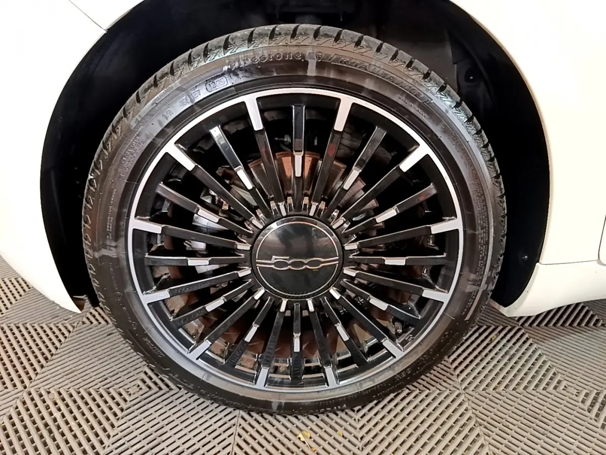 Gros plan sur la roue avant droite noire à jante multibranches du FIAT 500 blanc électrique 42kWh Icône 2022.