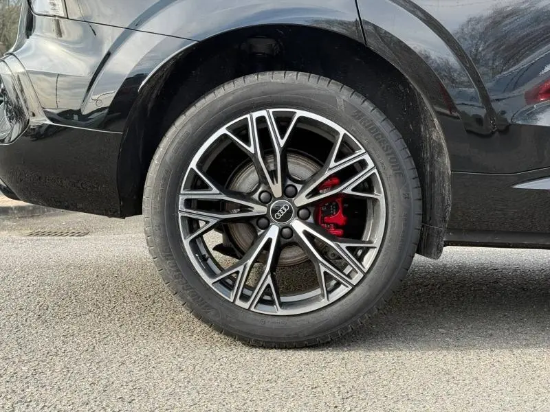 Gros plan sur la roue arrière droite d’un Audi Q3 2026 noir métallisé avec étrier de frein rouge et jante alliage S line.