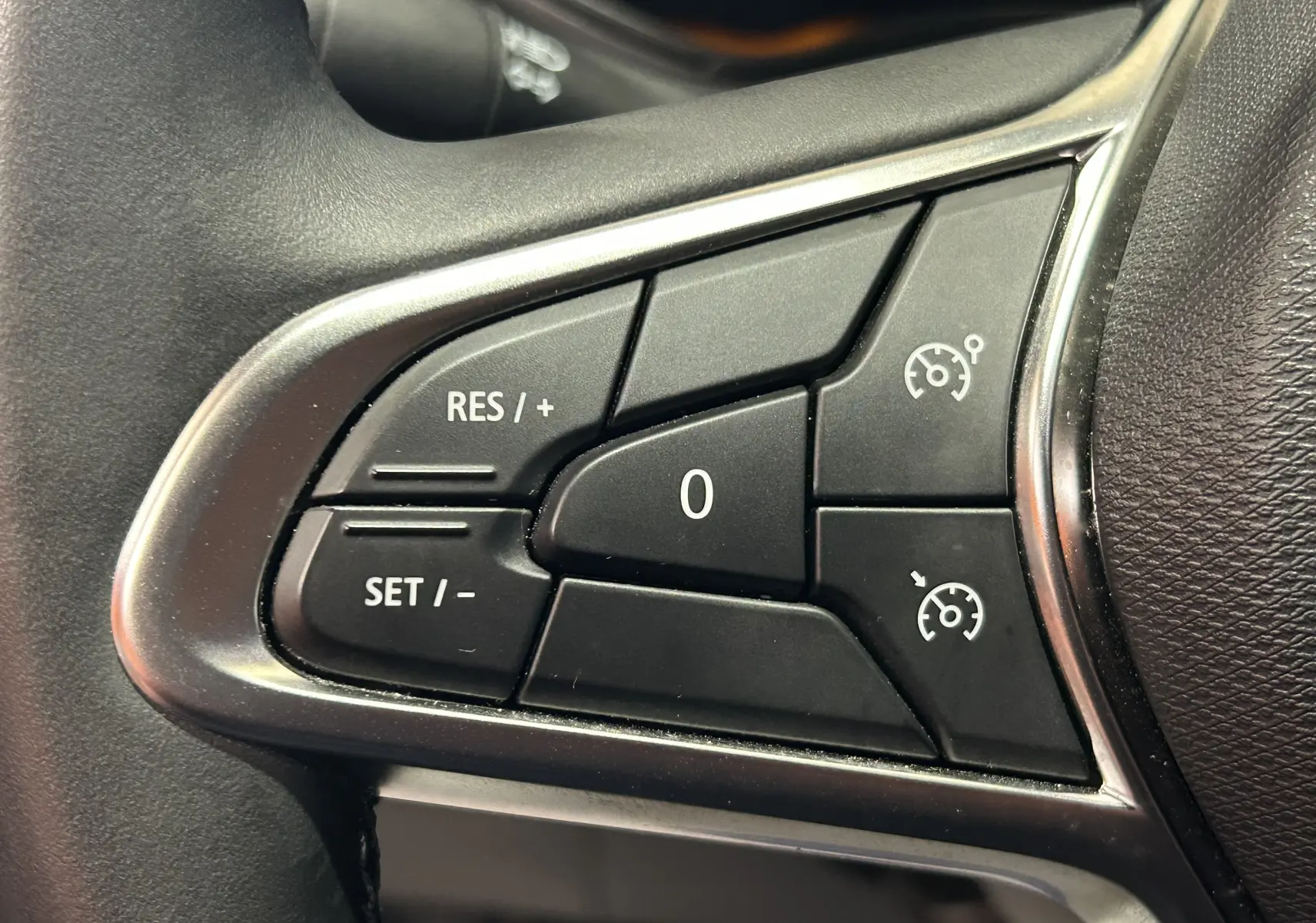 Gros plan sur les commandes de régulateur de vitesse au volant d’une Renault Clio V, finition noire.