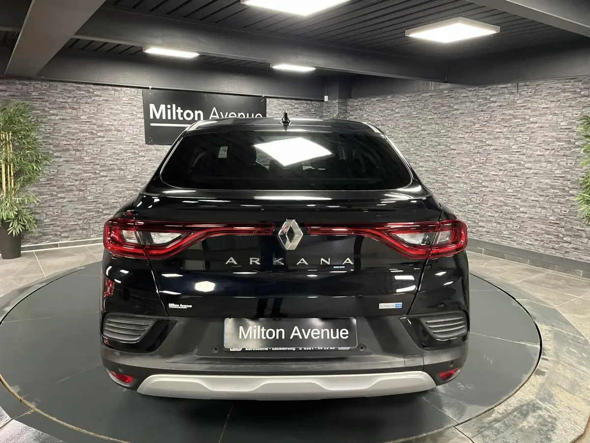 Vue arrière d'un Renault Arkana noir avec feux LED reliés et logo central dans un showroom.
