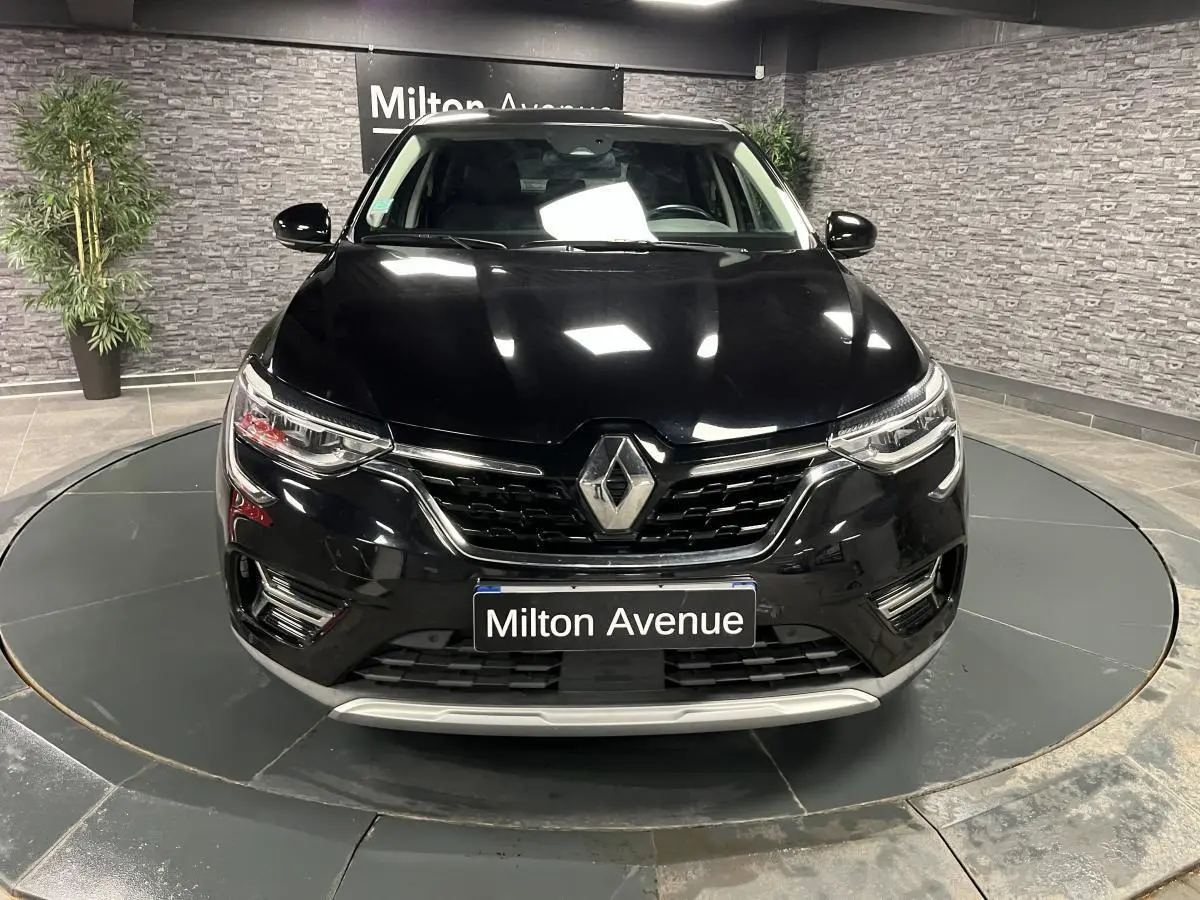 Vue frontale d'un Renault Arkana noir métal avec calandre chromée et phares Full LED Pure Vision allumés.