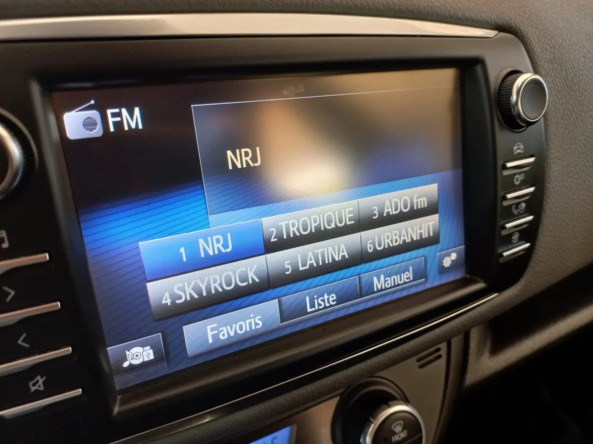 Écran tactile central de la Toyota Yaris blanche 2019 affichant les stations radio FM avec menu favoris.
