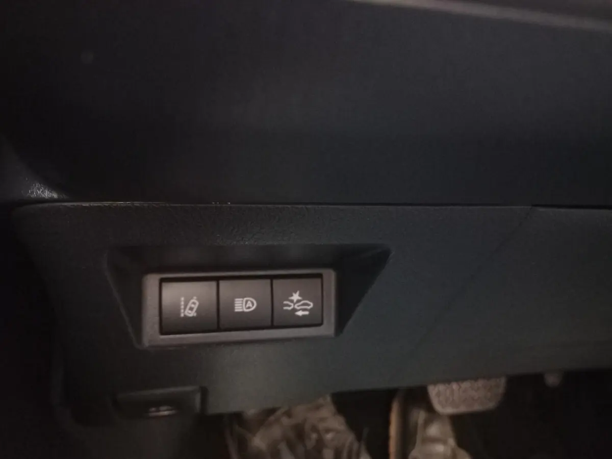 Gros plan sur les commandes de sécurité sous le tableau de bord d'une Toyota Yaris blanche hybride 2019.