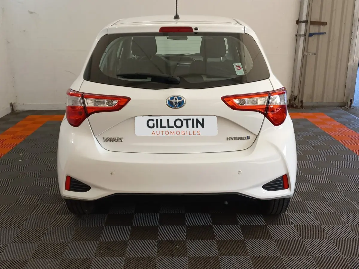 Vue arrière d'une Toyota Yaris blanche hybride 2019, avec feux arrière distinctifs et logo Toyota visible.