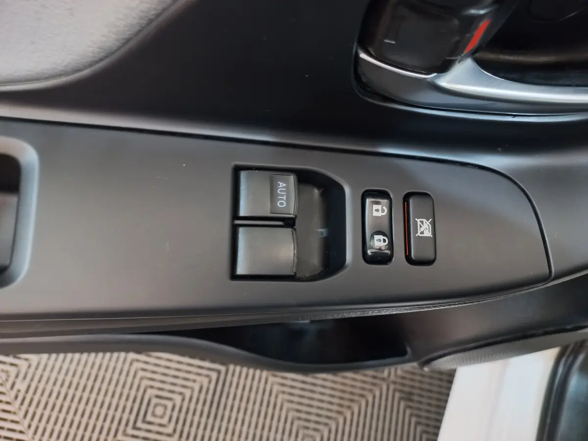 Gros plan sur les commandes de lève-vitres et verrouillage côté conducteur de la Toyota Yaris blanche 2019.