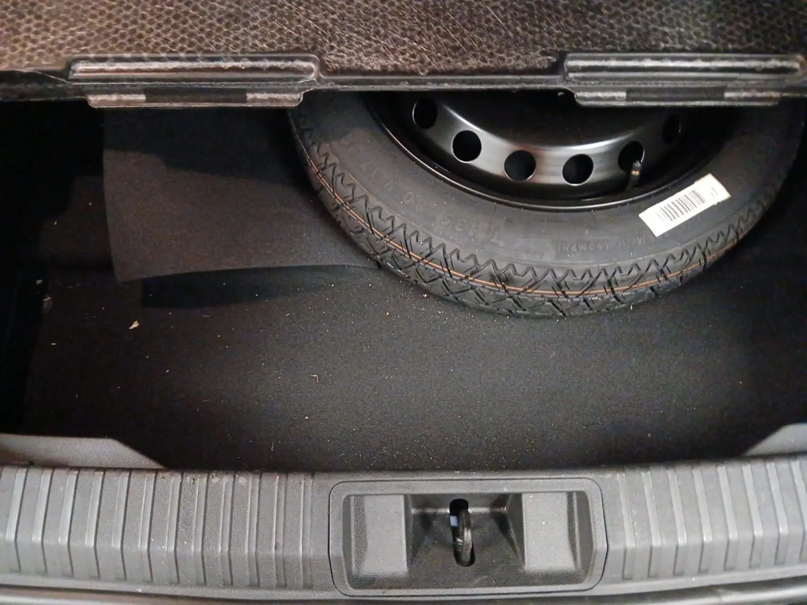 Vue rapprochée du coffre du Renault Symbioz 2025 bleu iron, montrant la roue de secours et le tapis noir.