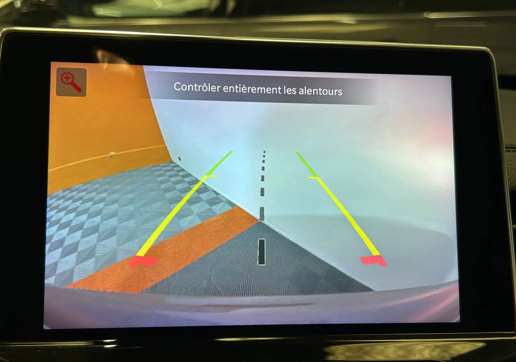 Affichage caméra de recul du Jeep Compass gris, vue arrière avec lignes de guidage jaunes et rouges sur sol carrelé.