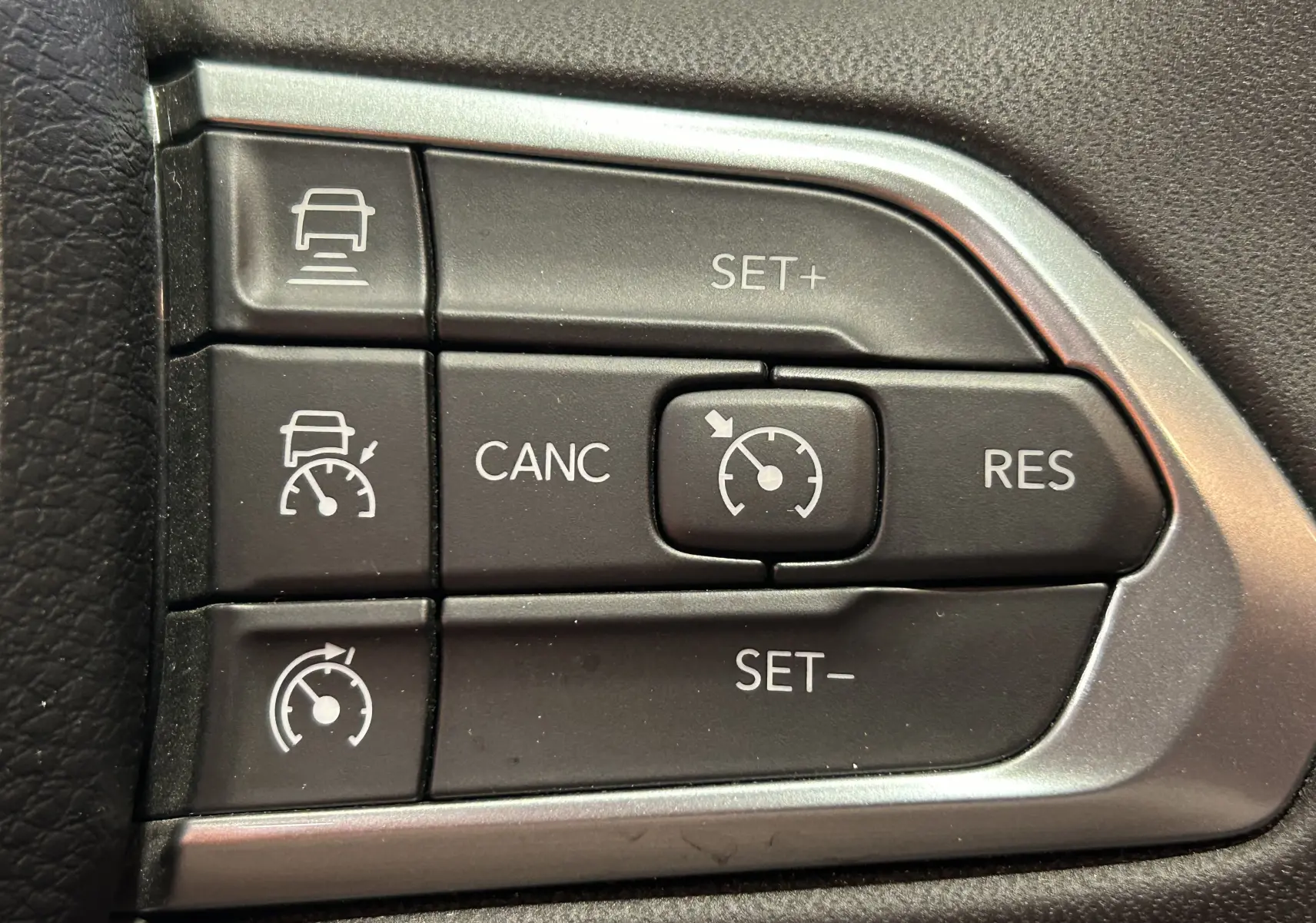 Boutons de régulateur de vitesse sur le volant du Jeep Compass Limited gris, vue rapprochée côté droit.