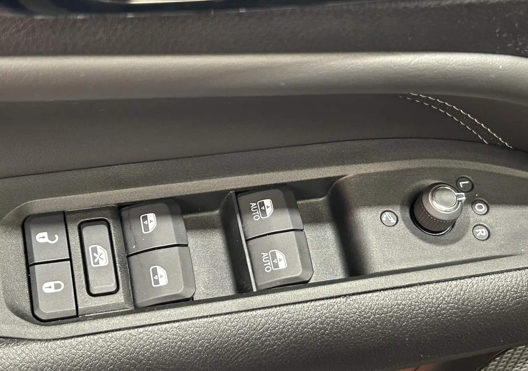 Commandes des vitres électriques et réglage des rétroviseurs sur la porte côté gauche d'un Jeep Compass gris 2021.