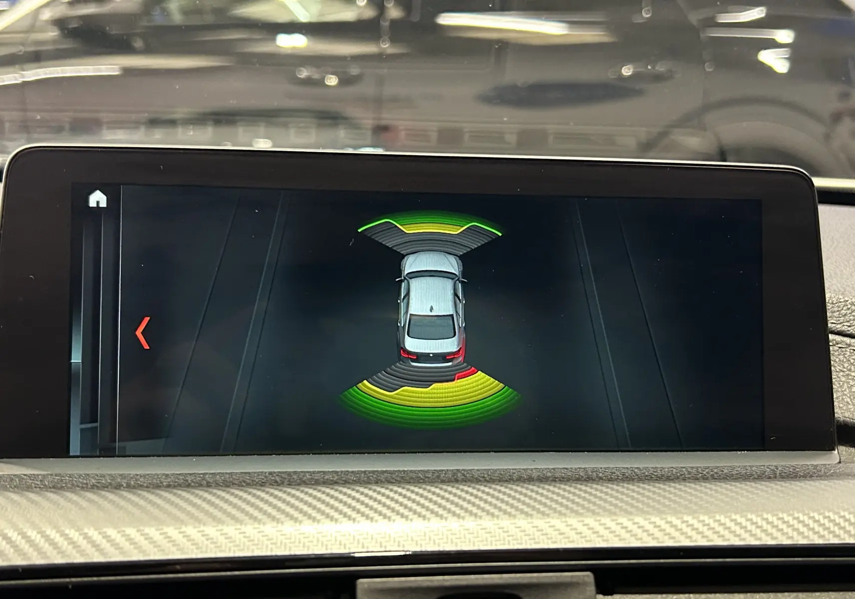 Écran central montrant l'aide au stationnement avec vue aérienne de la BMW Série 3 blanche en intérieur.