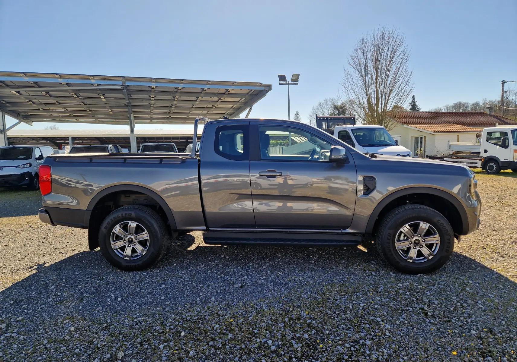 Vue de profil côté droit du Ford Ranger Super Cabine 4x4 gris carbone avec benne et jantes alliage 17 pouces.