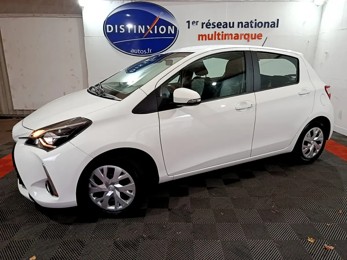 Toyota Yaris blanche 2020 vue de profil côté gauche dans un showroom avec éclairage intérieur.