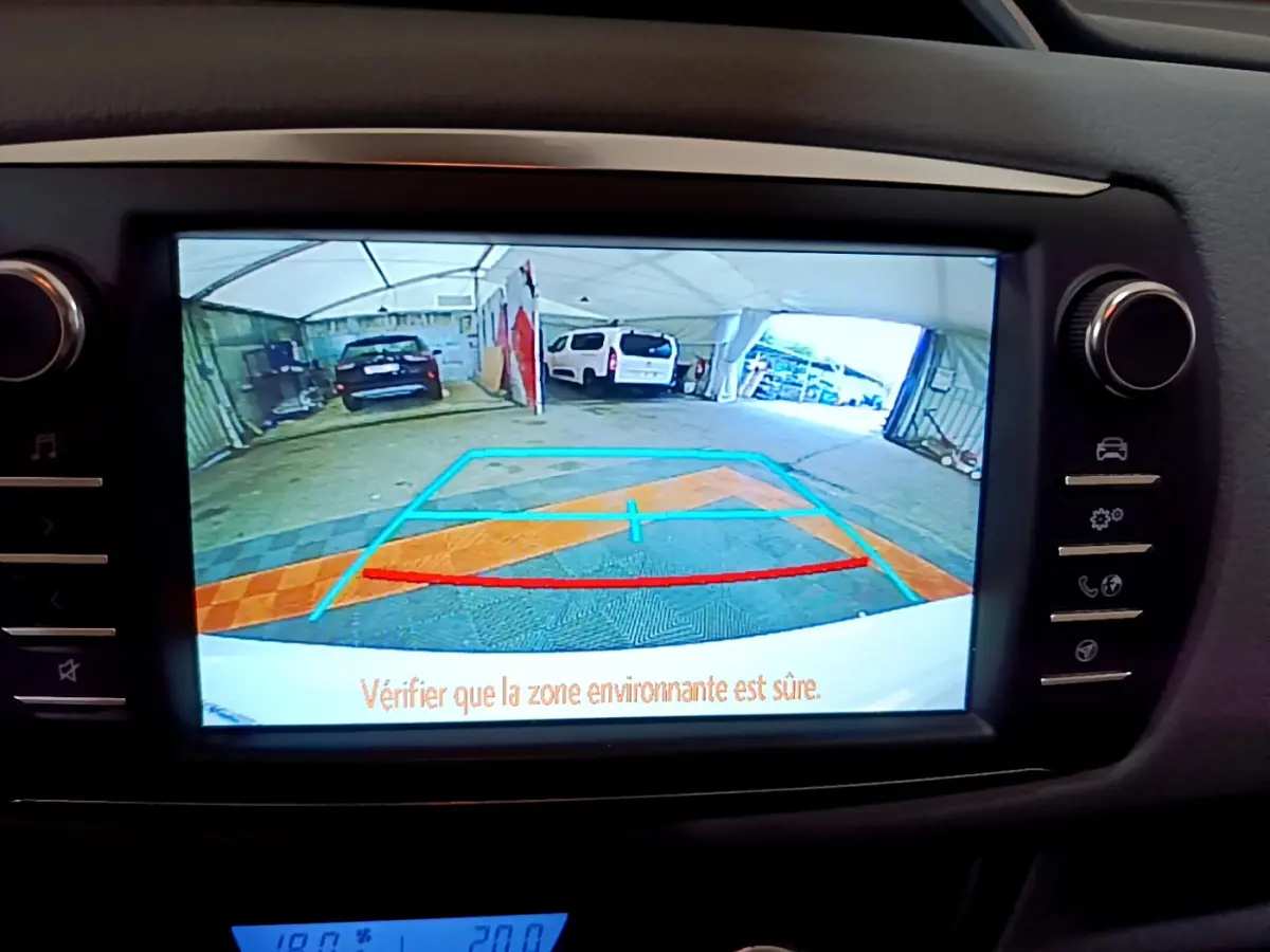 Vue de l'écran tactile central montrant la caméra de recul de la Toyota Yaris blanche, avec repères de stationnement colorés.