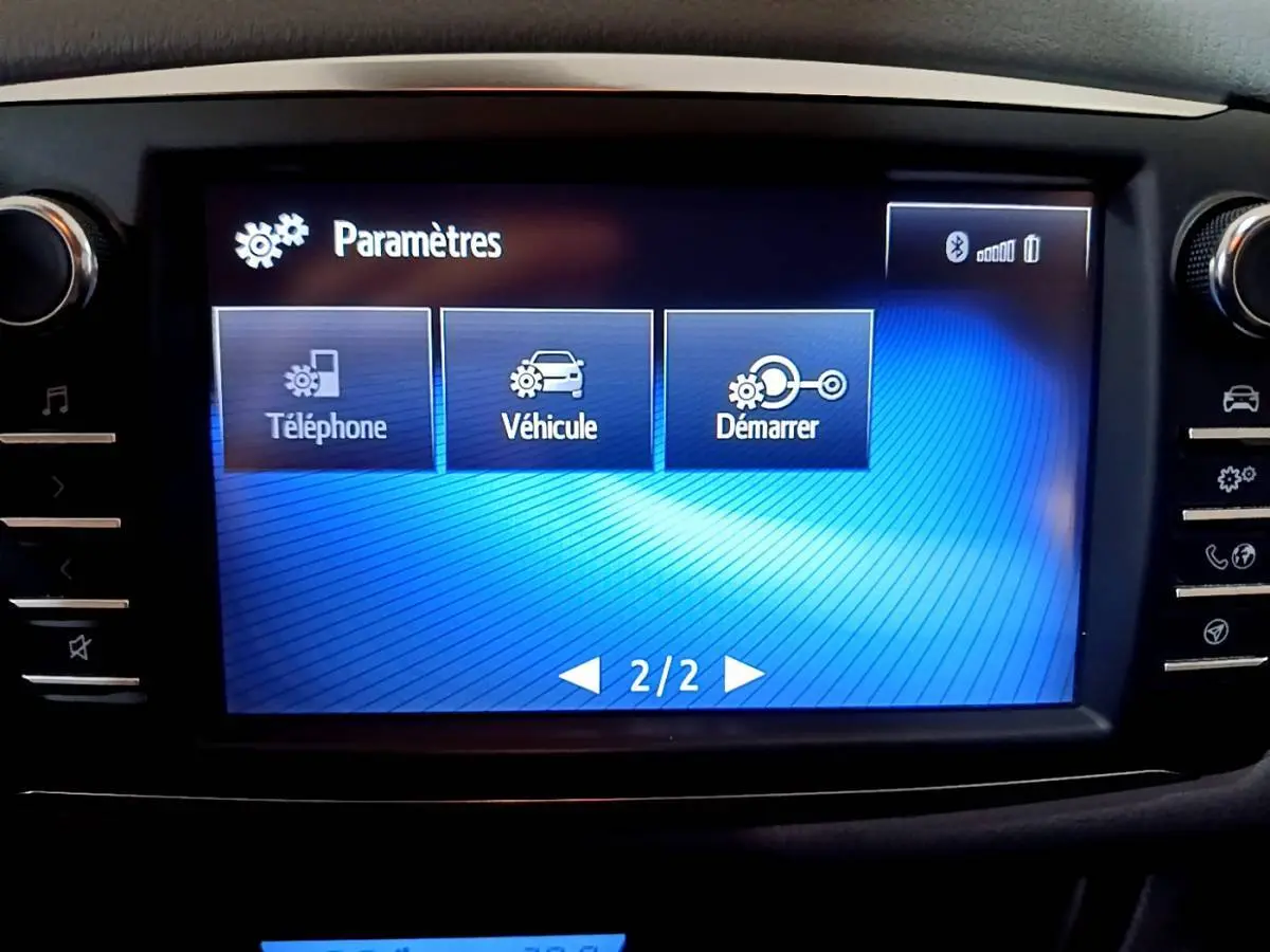 Écran tactile central bleu affichant le menu paramètres dans l'habitacle d'une Toyota Yaris blanche hybride 2020.
