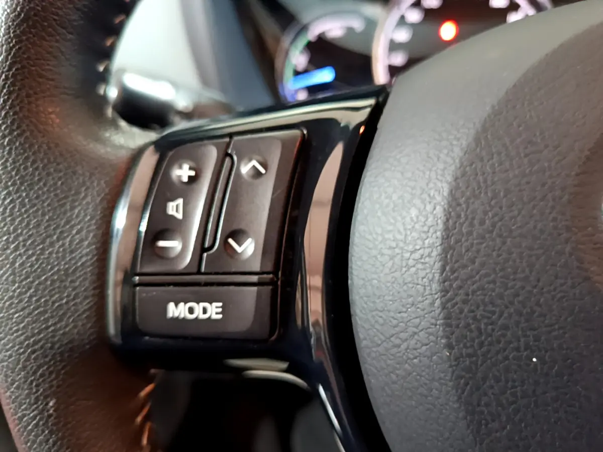 Gros plan sur les commandes du volant noir de la Toyota Yaris 1.5 Hybride 2020, avec boutons de volume et mode.