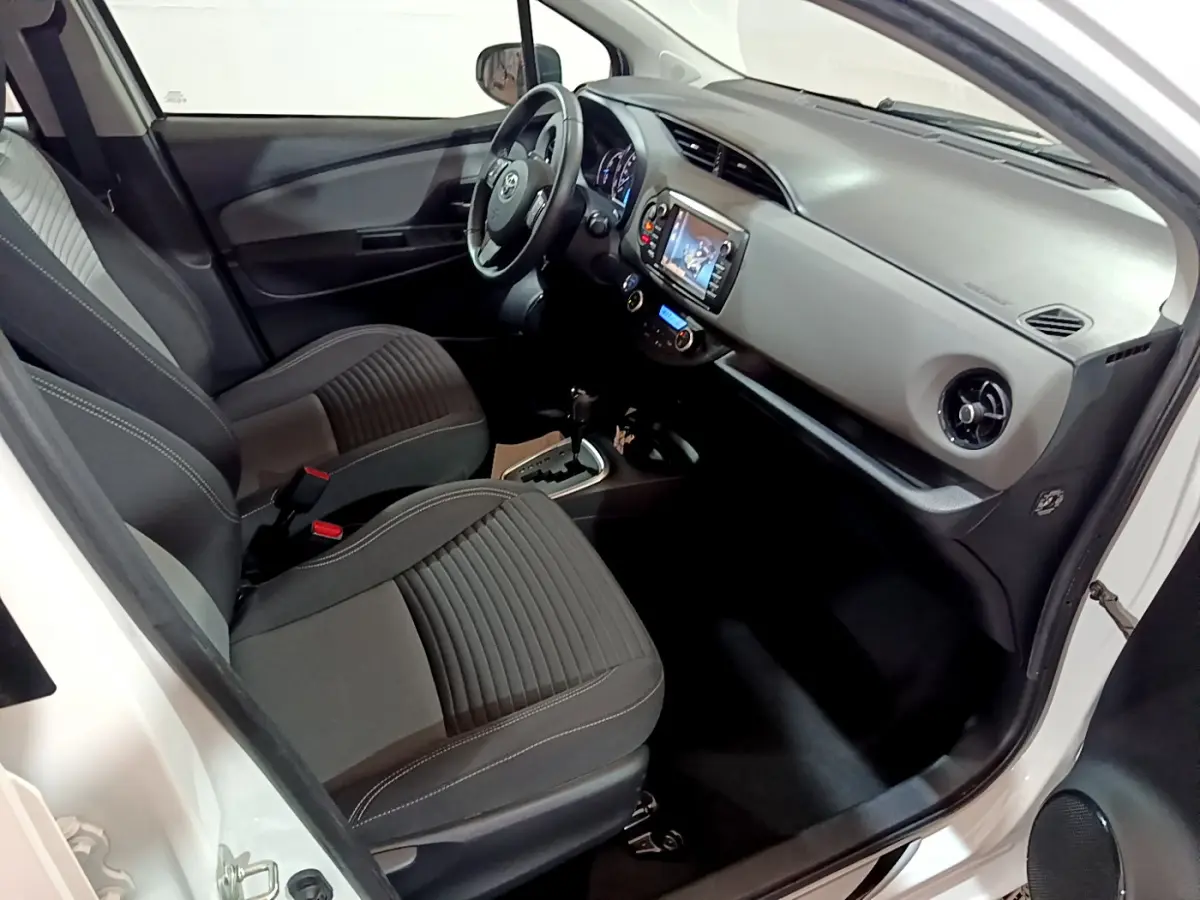 Vue intérieure côté conducteur de la Toyota Yaris blanche 2020, montrant sièges et tableau de bord moderne.