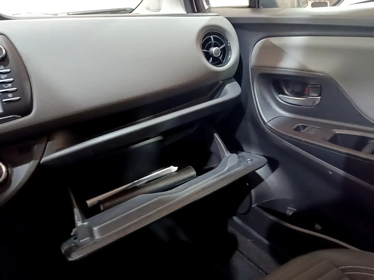 Vue intérieure côté passager de la Toyota Yaris blanche 2020, boîte à gants ouverte avec documents visibles.