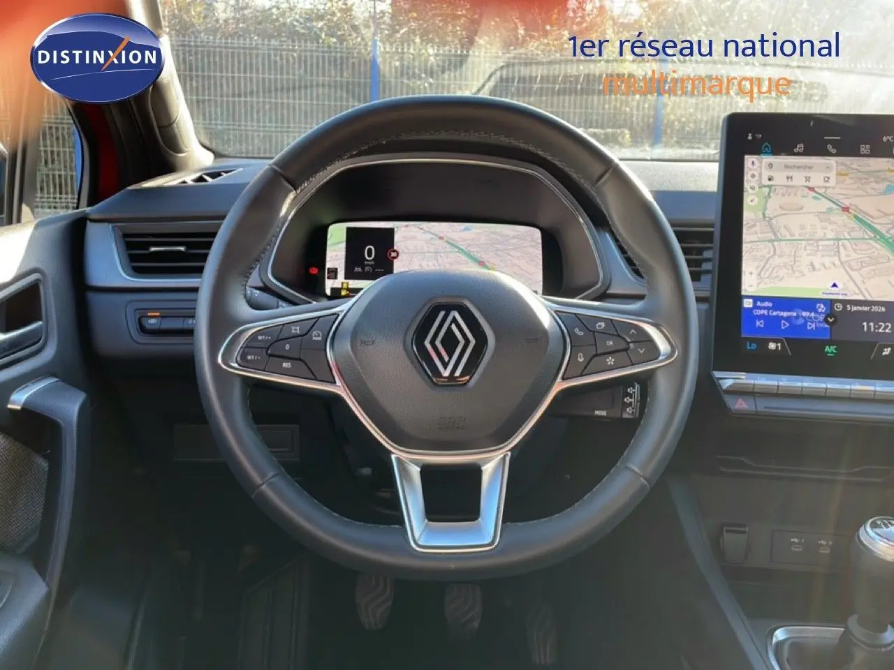 Vue centrée sur le volant et tableau de bord numérique du Renault Captur rouge Désir Métal avec toit noir, affichage GPS visible.