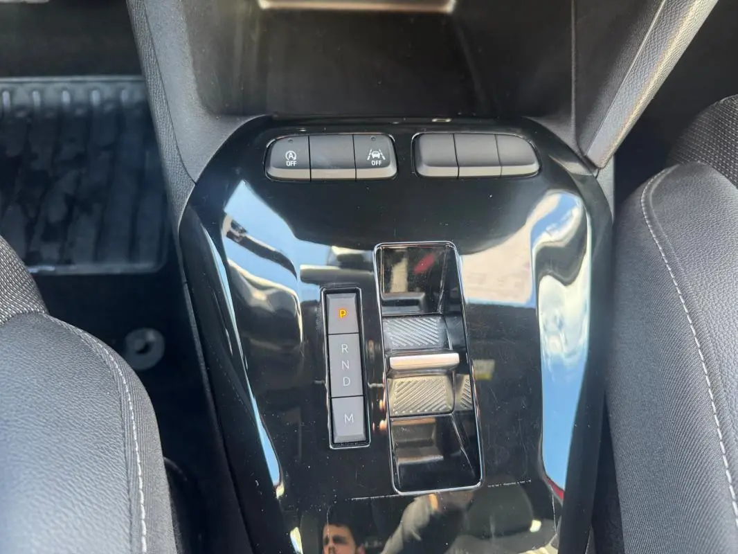 Vue rapprochée de la console centrale noire avec levier de boîte automatique et boutons de contrôle dans une Opel Corsa rouge.