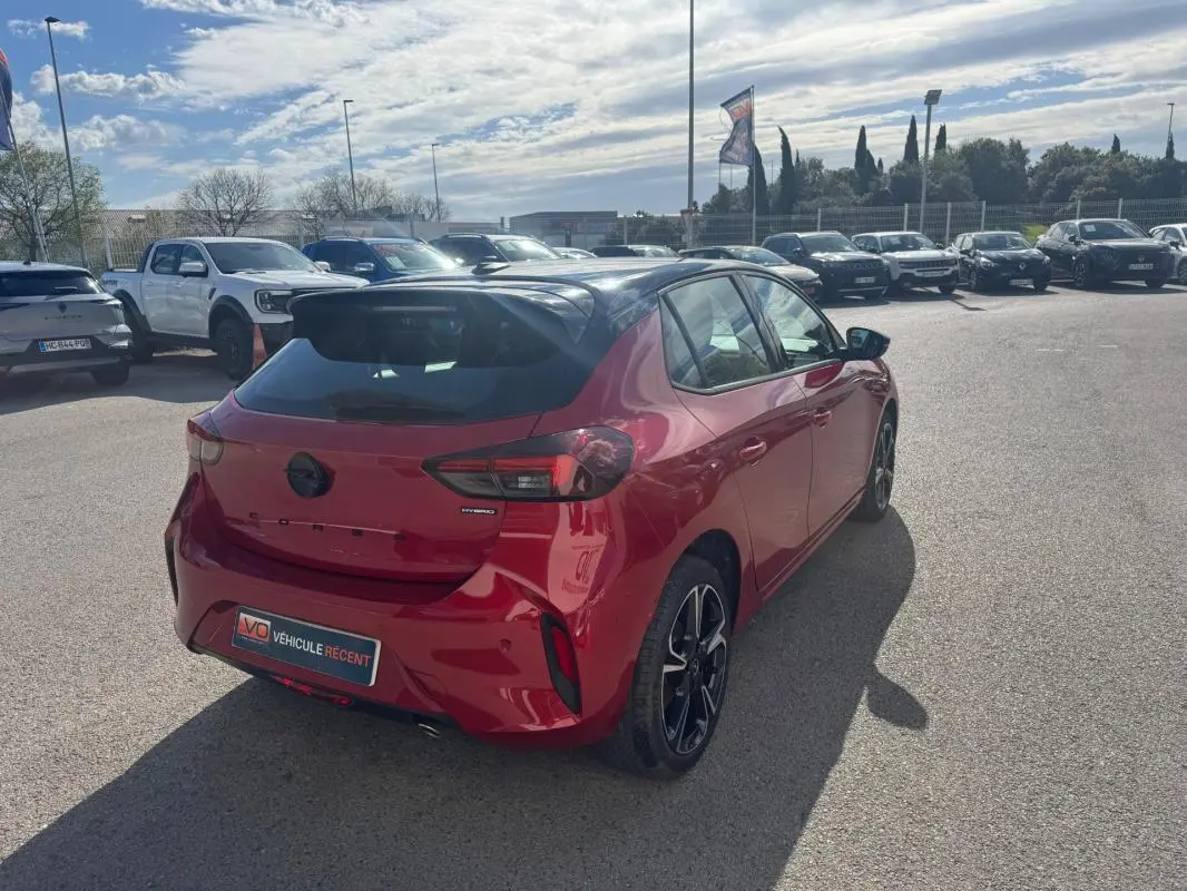 Vue 3/4 arrière droite d'une Opel Corsa rouge 2025 avec jantes alliage noires et feux arrière LED distinctifs.