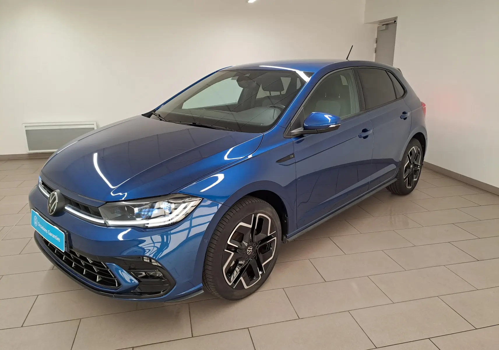 Volkswagen Polo 1.0 TSI R-Line bleu récif vue 3/4 avant droit en intérieur avec jantes distinctives.
