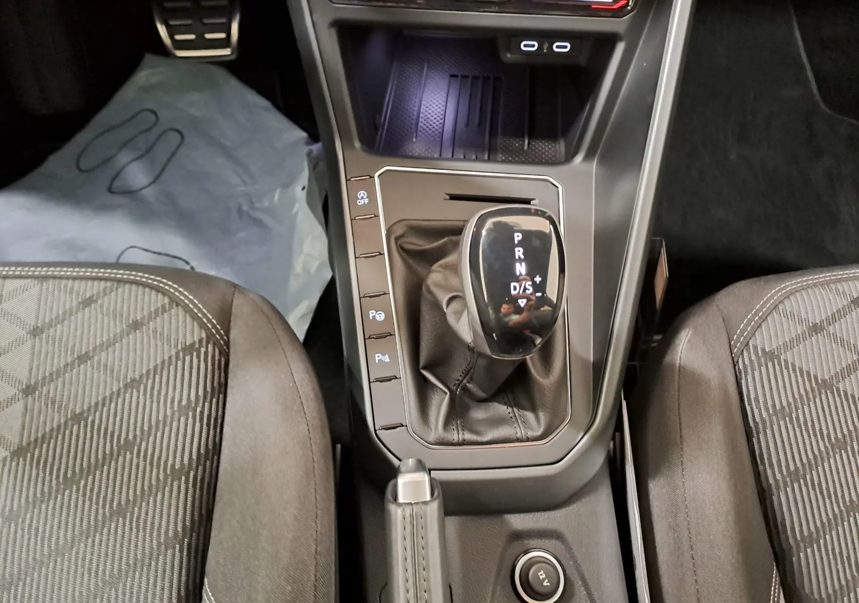 Vue plongeante sur la console centrale de la Volkswagen Polo 2025, avec levier de vitesse automatique et sièges tissu gris.
