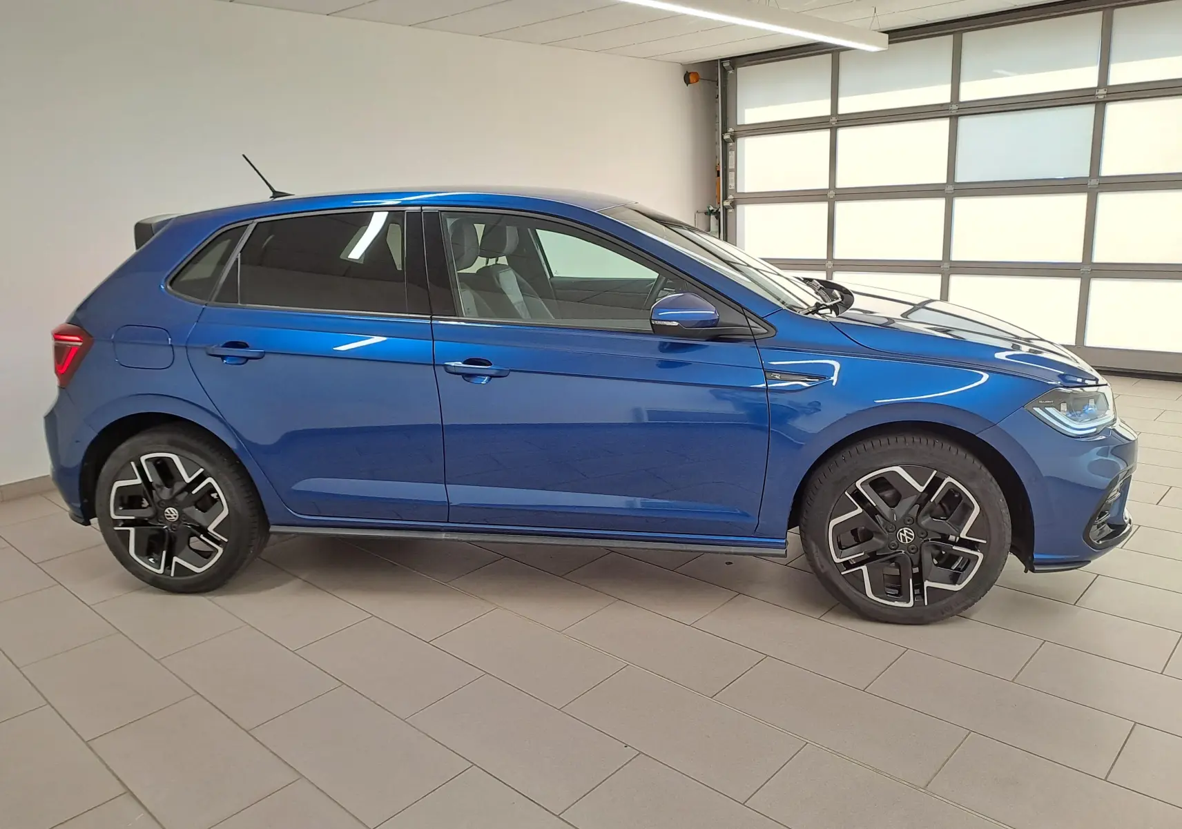 Volkswagen Polo 1.0 TSI R-Line bleu récif vue de profil côté gauche avec jantes noires distinctives.