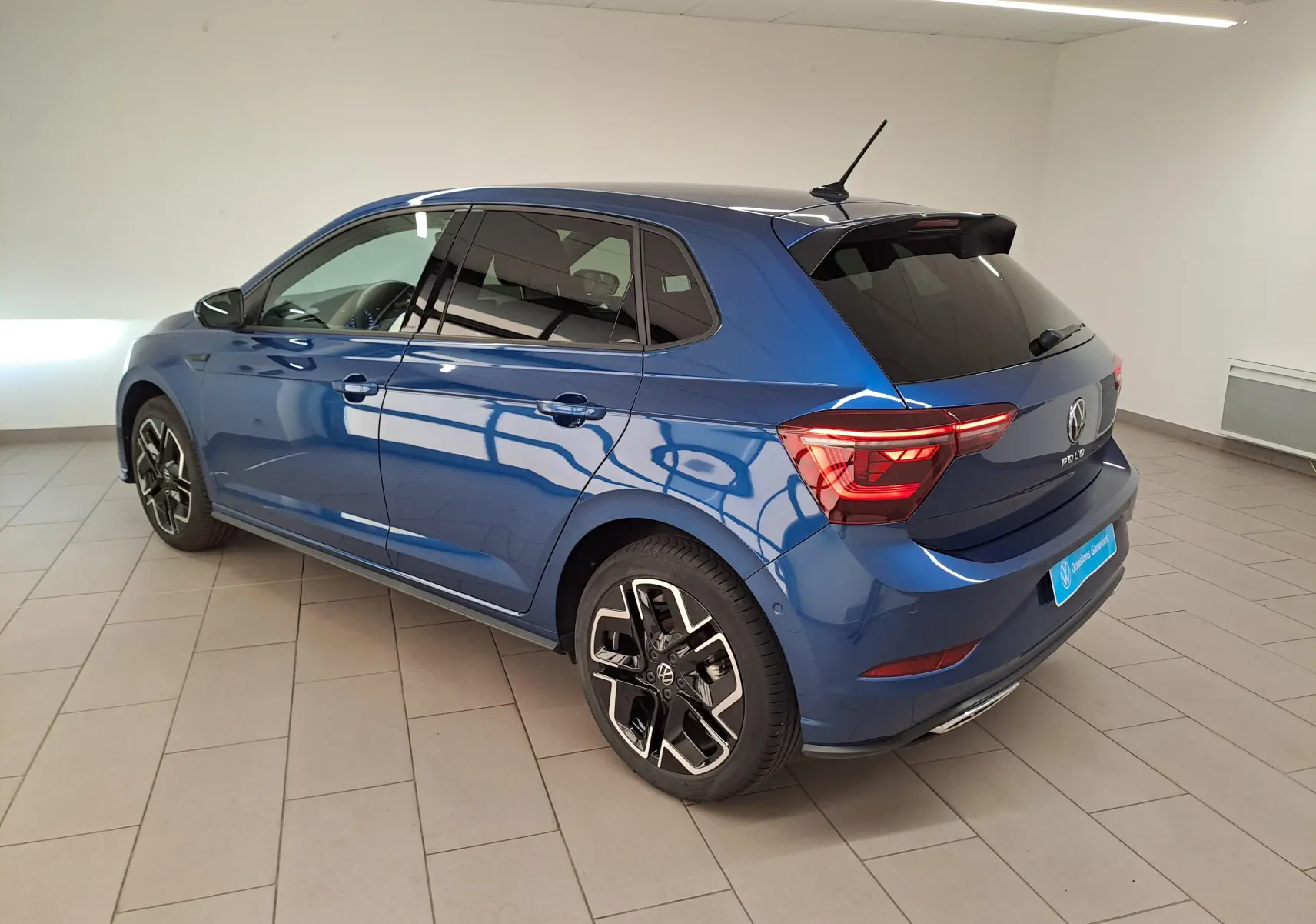 Vue 3/4 arrière droite d'une Volkswagen Polo 2025 Bleu Récif métallisé avec jantes R-Line distinctives en intérieur neutre.